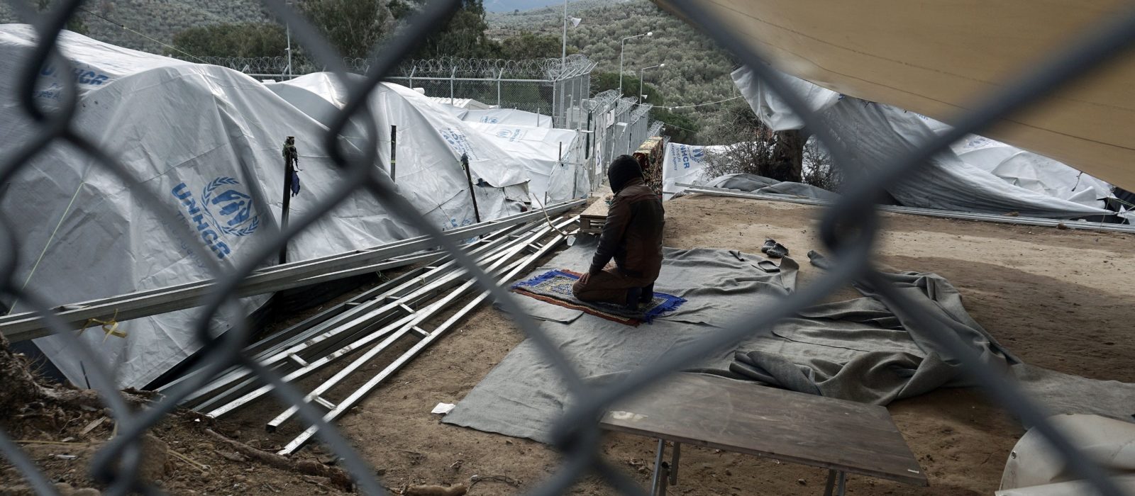 A man prays in the Moria migrant camp on the Greek island of Lesbos on December 30, 2016.
There are over 60,000 refugees and migrants trapped in Greece after EU and Balkan countries further north shut their borders nearly a year ago. / AFP / STR        (Photo credit should read STR/AFP/Getty Images)
