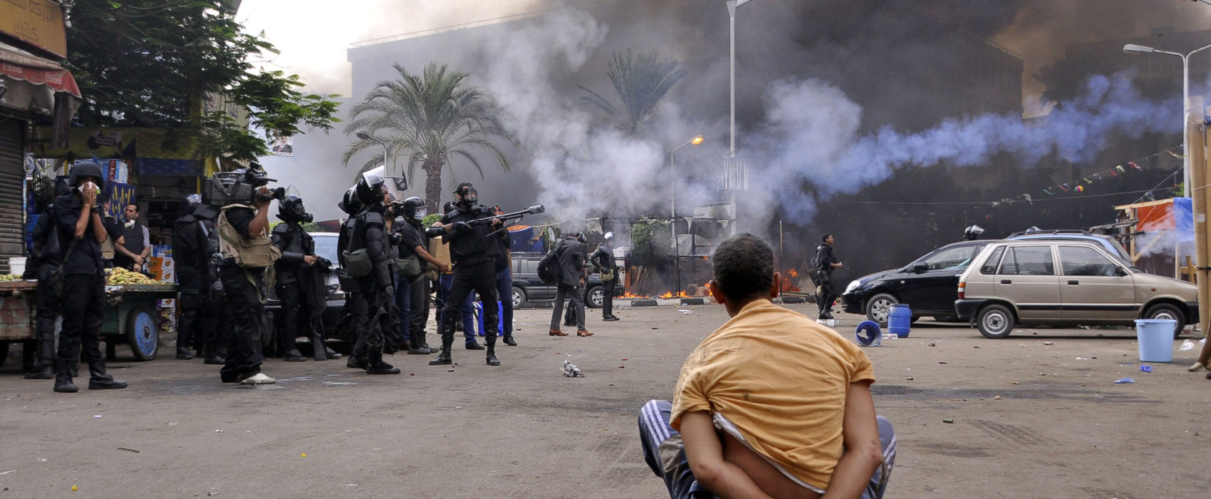 A handcuffed protester sits on the ground as Egyptian security forces move in to disperse supporters of Egypt's ousted president Mohamed Morsi by force in a huge camp in Cairo's Al-Nahda square on August 14, 2013. The operation began shortly after dawn when security forces surrounded the sprawling Rabaa al-Adawiya camp in east Cairo and a similar one at Al-Nahda square, in the centre of the capital, launching a long-threatened crackdown that left dozens dead. AFP PHOTO / ENGY IMAD        (Photo credit should read Engy Imad/AFP/Getty Images)