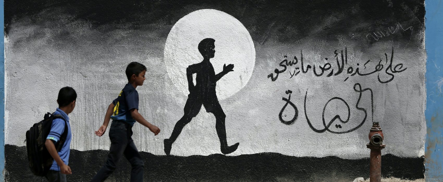 Two Palestinian schoolboys walk past a graffiti painted on a wall of the United Nations school of Beit Hanun, in the northern Gaza Strip, on May 9, 2016.  / AFP / THOMAS COEX        (Photo credit should read THOMAS COEX/AFP/Getty Images)