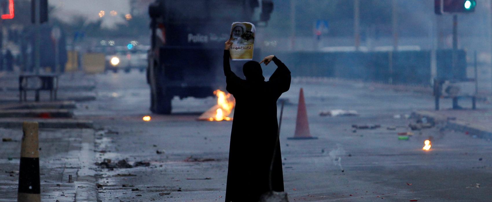 A female protester holds a photo of Shi'ite scholar Isa Qassim as she confronts riot police armoured personnel carrier during a demonstration to mark the 6th anniversary of the February 14 uprising, in the village of Sitra, south of Manama, Bahrain February 14, 2017. REUTERS/Hamad I Mohammed - RTSZMG2