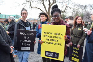 Bel, a young activist for Amnesty Ireland holding a placard that says 'We don't have a refugee crisis. We have a housing crisis.'