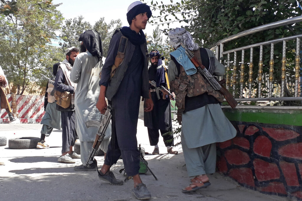 Taliban fighters stand along the roadside in Ghazni