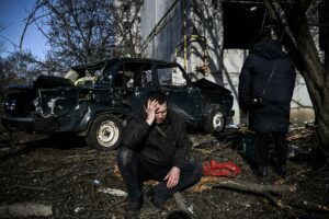 TOPSHOT - A man sits outside his destroyed building after airstrikes on the Eastern Ukraine town of Chuguiv on February 24, 2022, as Russian armed forces are trying to invade Ukraine from several directions, using rocket systems and helicopters to attack Ukrainian position in the south, the border guard service said. - Russia's ground forces today crossed into Ukraine from several directions, Ukraine's border guard service said, hours after President Vladimir Putin announced the launch of a major offensive. Russian tanks and other heavy equipment crossed the frontier in several northern regions, as well as from the Kremlin-annexed peninsula of Crimea in the south, the agency said. (Photo by Aris Messinis / AFP) (Photo by ARIS MESSINIS/AFP via Getty Images)