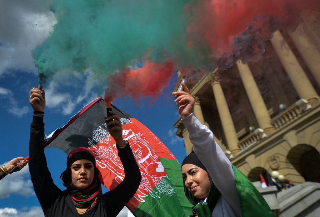 Protesters light flares in the colors of Afghanistan in Edmonton Canada to protest Taliban rule