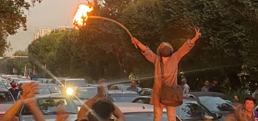 A protestor climbs on to a car in Iran