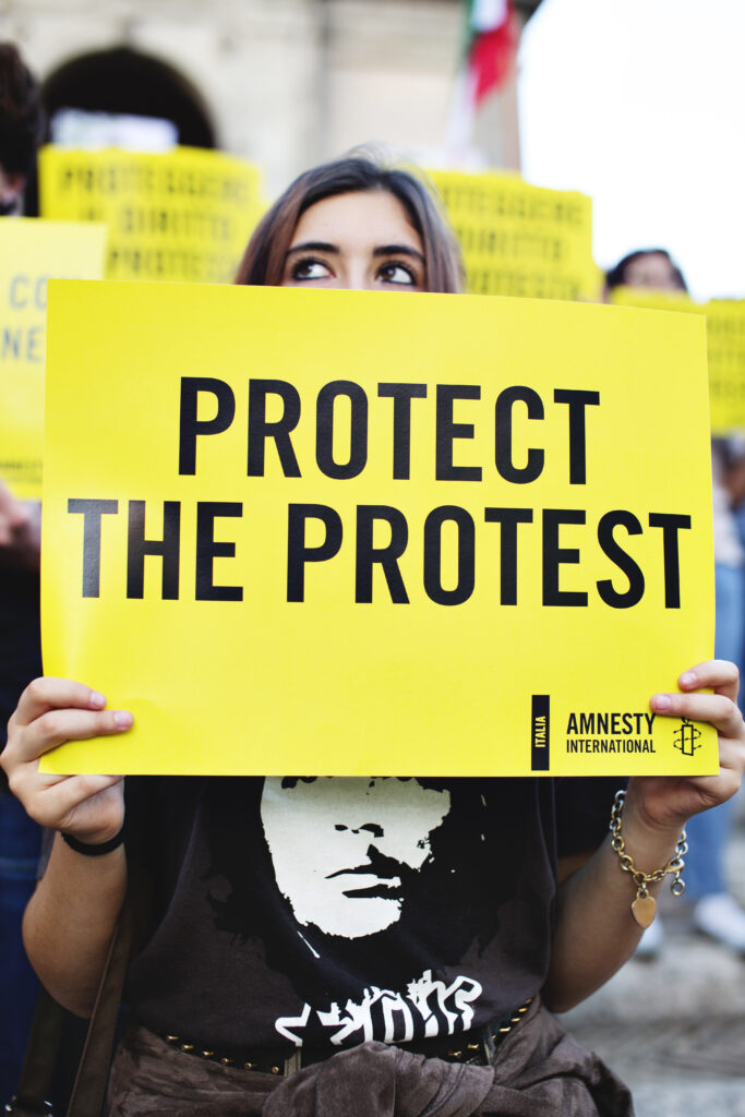 A protestor holds a protect the protest sign