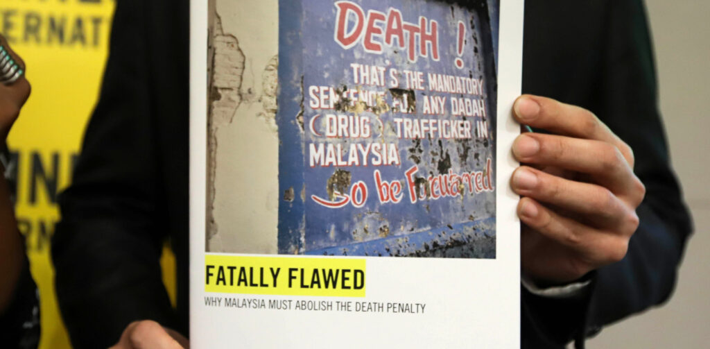 Brian Yap, research consultant of Amnesty International Malaysia, holds a copy of a report on the death penalty in Malaysia, during its launch in Petaling Jaya on October 10, 2019. - Malaysian police sometimes use torture to extract confessions from suspects in death penalty cases, who often face unfair trials, Amnesty International said on October 10, piling pressure on the government to abolish capital punishment.