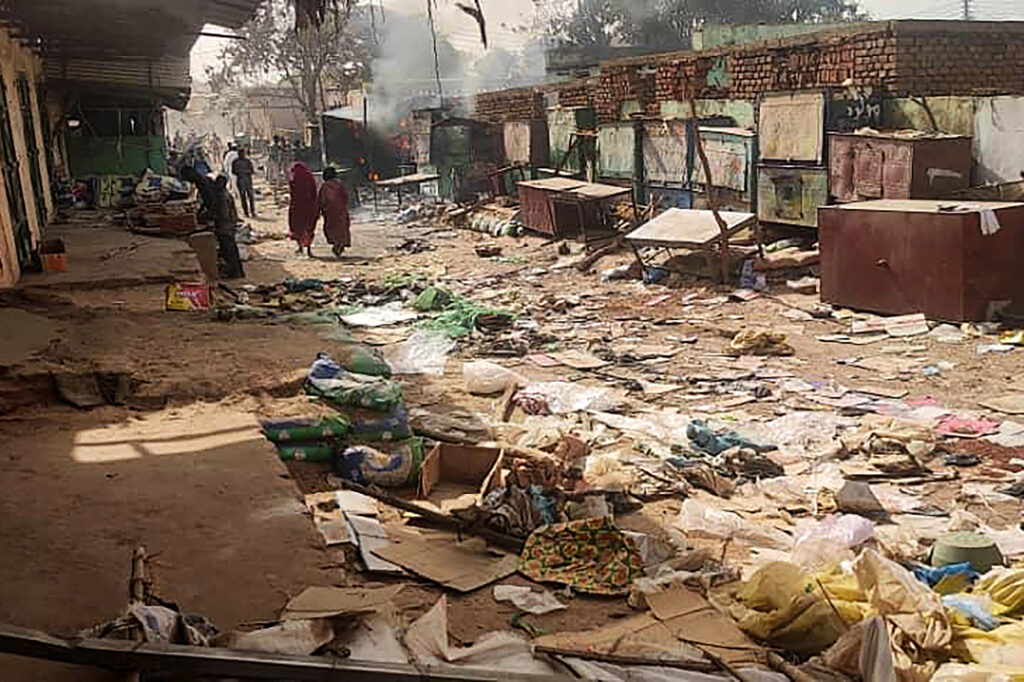 People walk among scattered objects in the market of El Geneina, the capital of West Darfur, as fighting continues in Sudan between the forces of two rival generals, on April 29, 2023. - At least 96 people were reported to have been killed in El Geneina this week, the UN said, as fierce fighting between Sudan's army and paramilitaries entered a third week, violating a renewed truce.