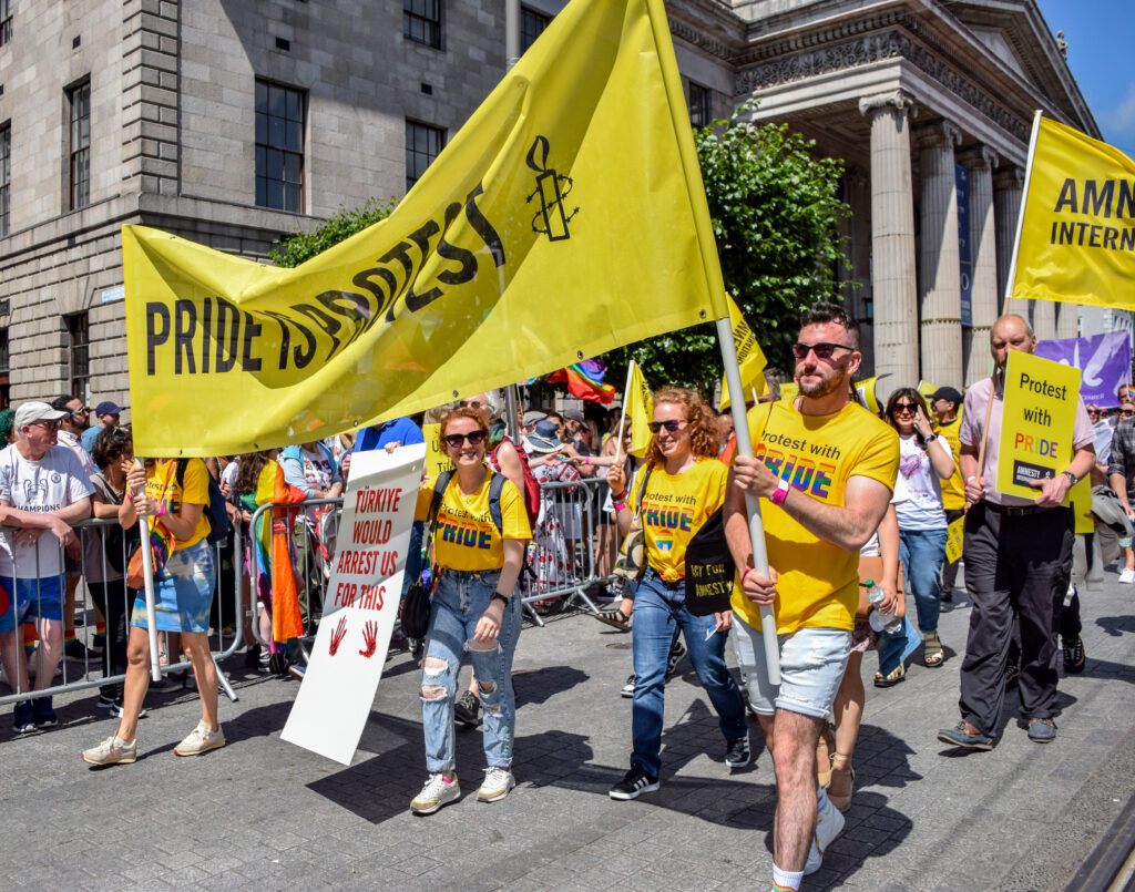 Amnesty activists march in Dublin Pride holding a banner that reads Pride is Protest