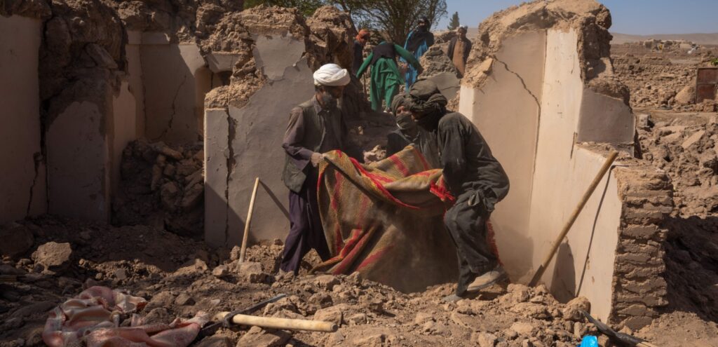 Three men huddle in the wreckage after the earthquake in Afghanistan