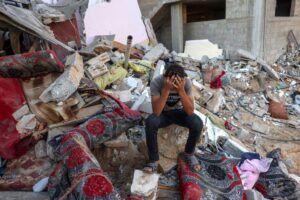 TOPSHOT - A Palestinian youth reacts as he sits on the rubble of a destroyed home following an Israeli military strike on the Rafah refugee camp, in the southern of Gaza Strip on Octobers 15, 2023, amid the ongoing battles between Israel and the Palestinian Islamist group Hamas. Thousands of people, both Israeli and Palestinians have died since October 7, 2023, after Palestinian Hamas militants based in the Gaza Strip, entered southern Israel in a surprise attack leading Israel to declare war on Hamas in Gaza on October 8. (Photo by MOHAMMED ABED / AFP)