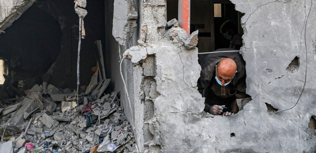 A man lies in the wreckage of a home in Gaza following bombing by forces from Israel