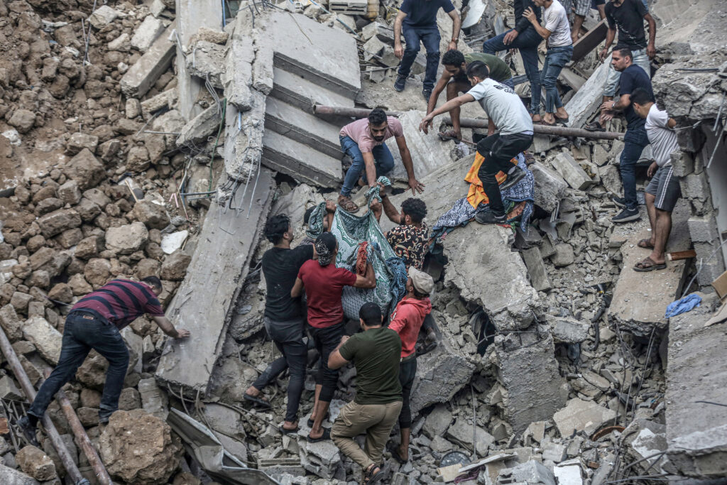 GAZA CITY, GAZA - OCTOBER 20: People carry a dead body pulled from rubble as civil defense teams and residents continue search and rescue efforts in the historical Greek Orthodox Saint Porphyrius Church, where civilians took shelter, after Israeli airstrike in Gaza City, Gaza on October 20, 2023. At least eight people were killed in an overnight Israeli airstrike on the Greek Orthodox Saint Porphyrius Church in Gaza city, which was sheltering hundreds of Palestinians, local media reported on Friday. (Photo by Ali Jadallah/Anadolu via Getty Images)