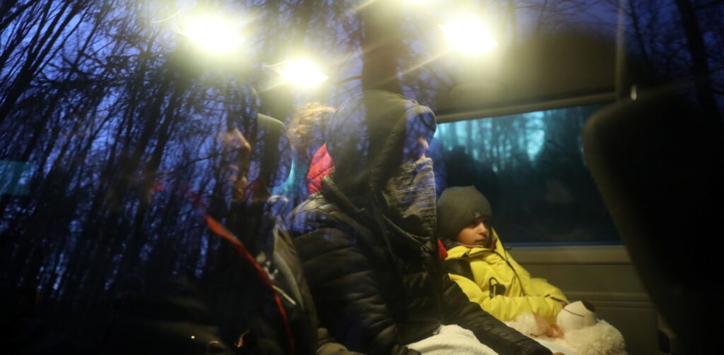A boy and a father on a bus, wrapped up warm, through a window